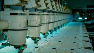 Row of industrial sewing machines in a textile factory producing garments.